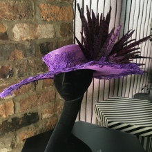 purple wide brim hat trimmed with lace and feathers